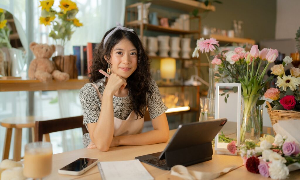 Woman sitting at a desk with a phone, tablet, and other office supplies.