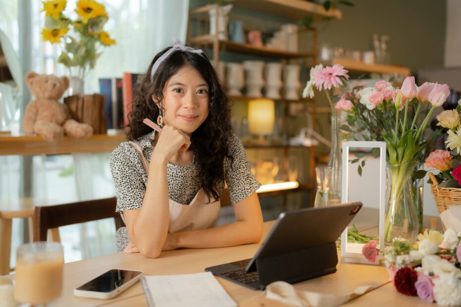 Woman sitting at a desk with a phone, tablet, and other office supplies.