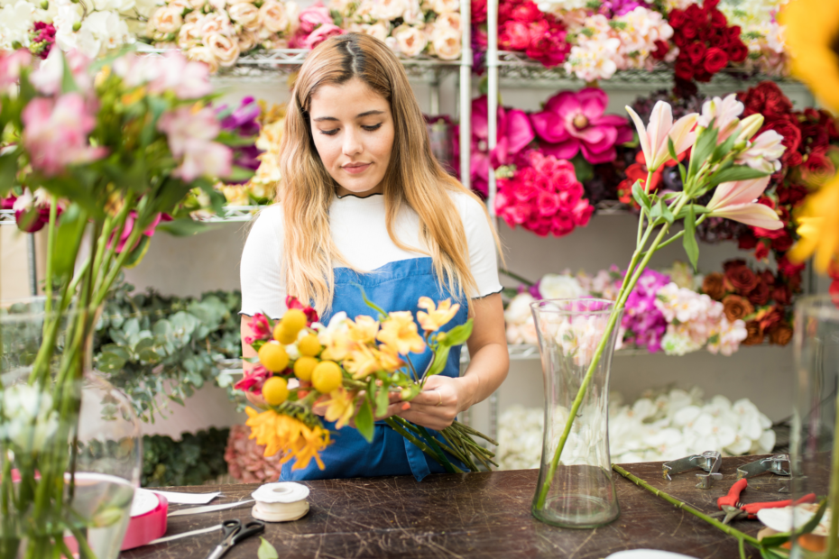 Florist holding flowers while she designs a vase arrangement