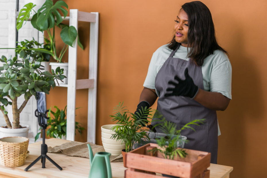 A florist is filming herself with a camera on a tripod while she works on arranging plants