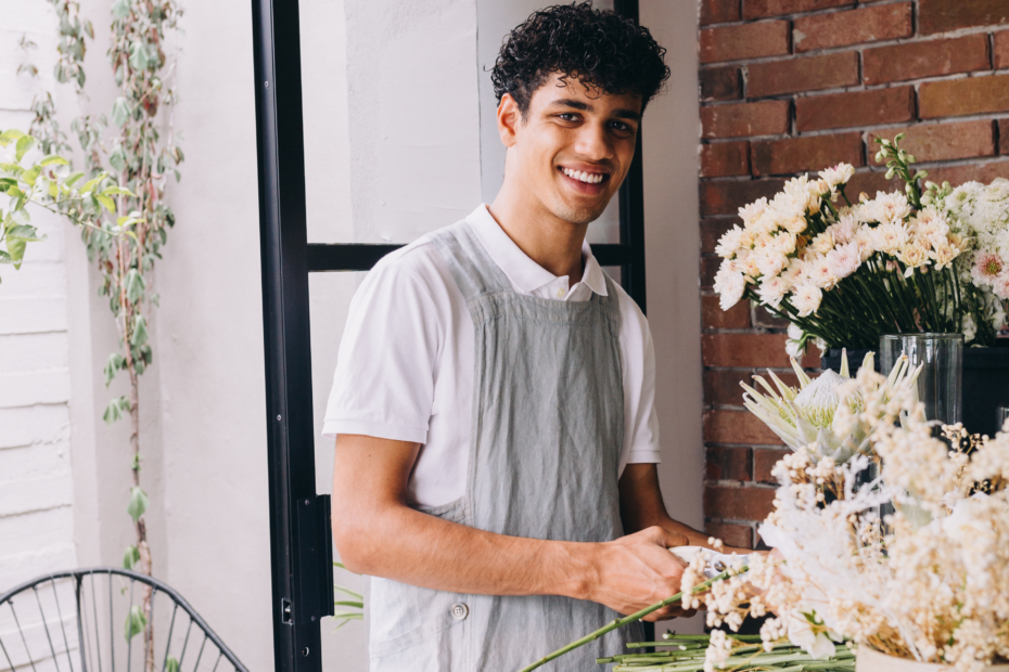male florist with buckets of white flowers cutting stems