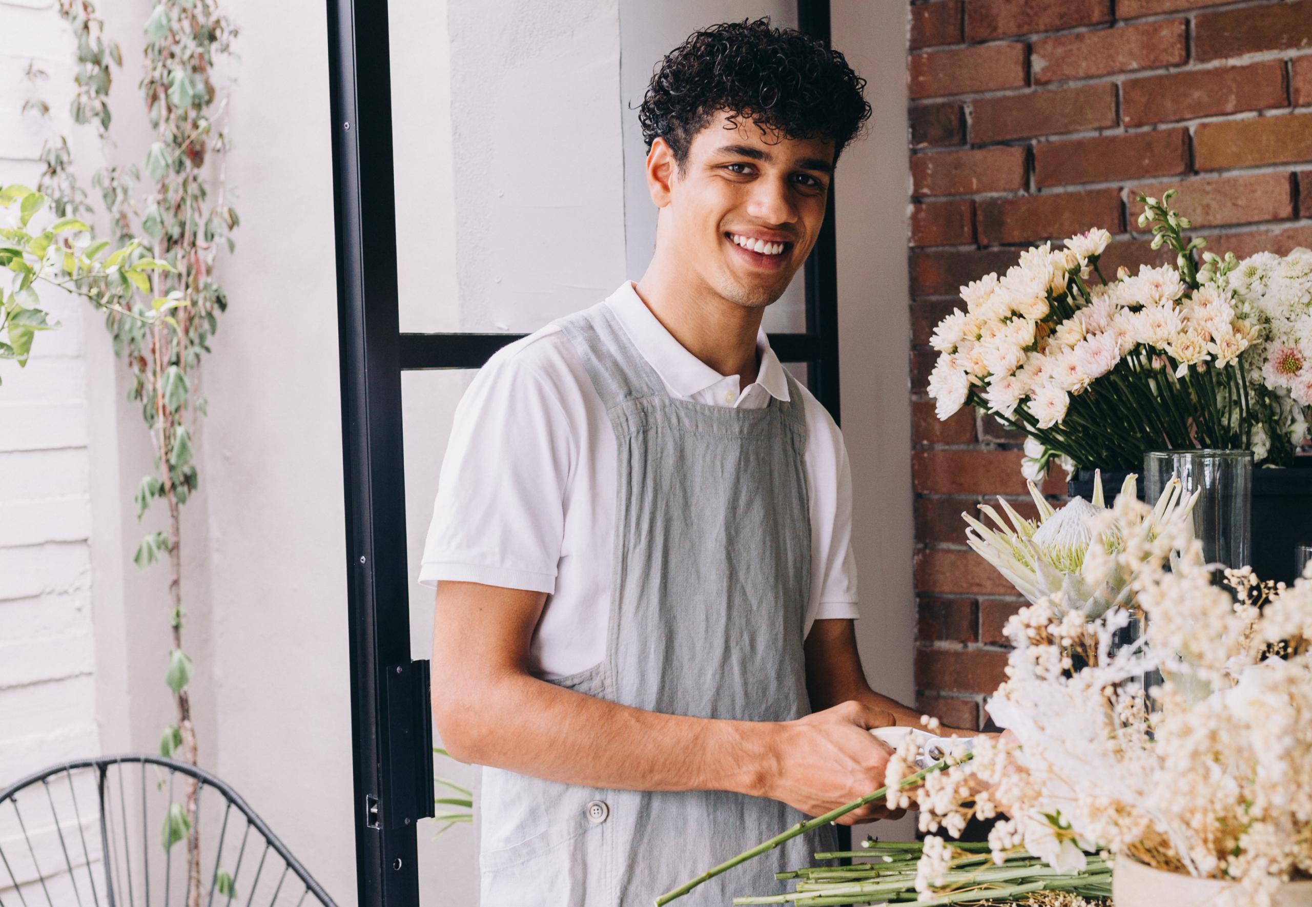 male florist with buckets of white flowers cutting stems
