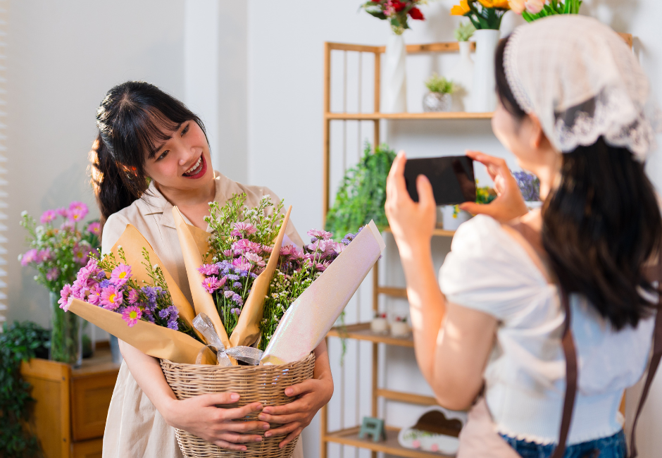 woman taking a photo of another woman with flower bouquets