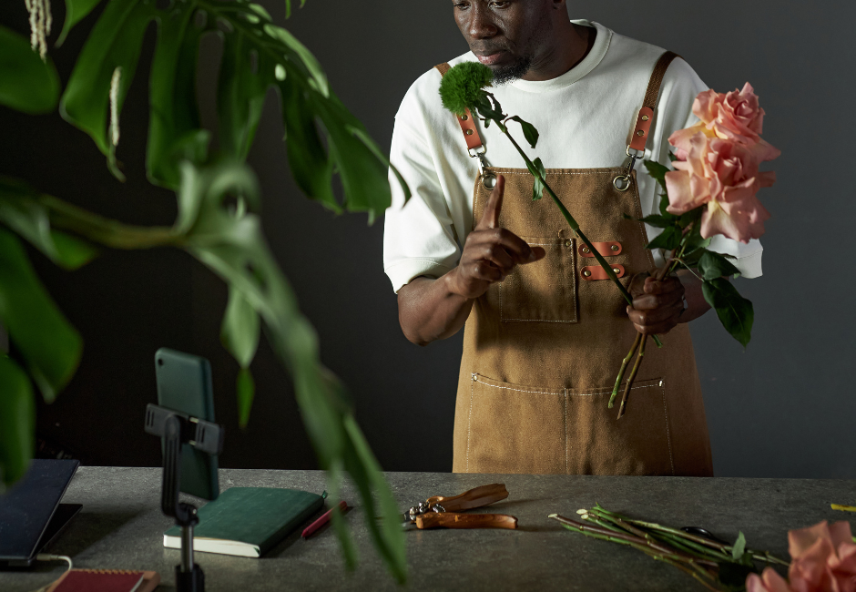 male florist arranging flowers with a phone set up on a tripod