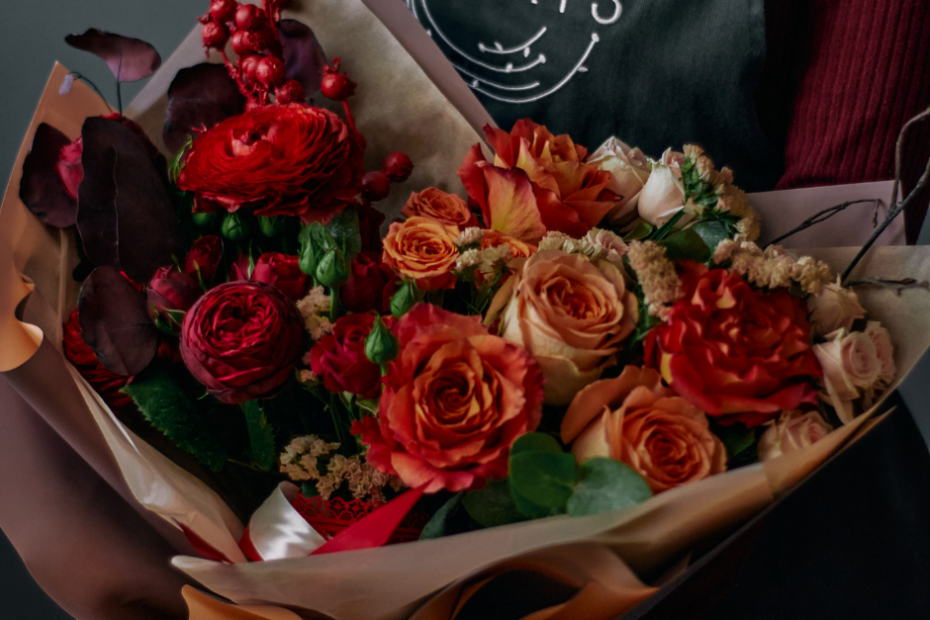 How to Build a Simple Monthly Marketing Plan for Your Flower Shop 1 florist holding a bouquet of orange and red roses