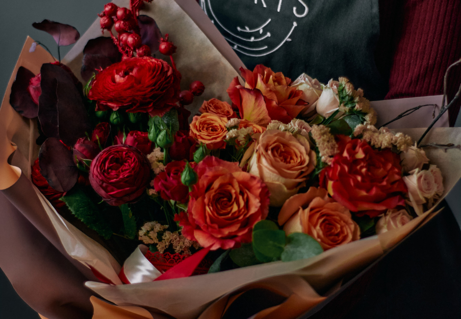 florist holding a bouquet of orange and red roses